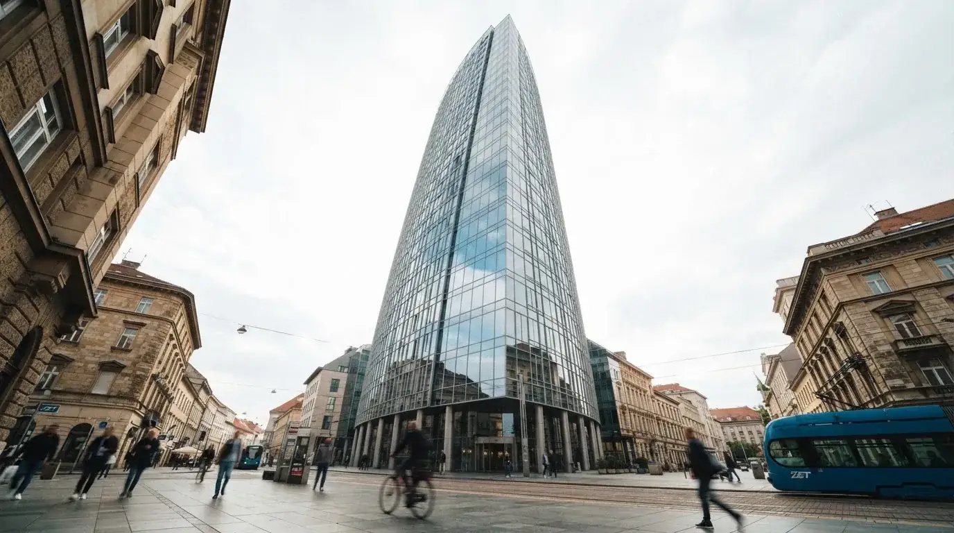 Neboder u središtu Zagreba s odsjajem neba na staklenom pročelju, snimljen s razine ulice.